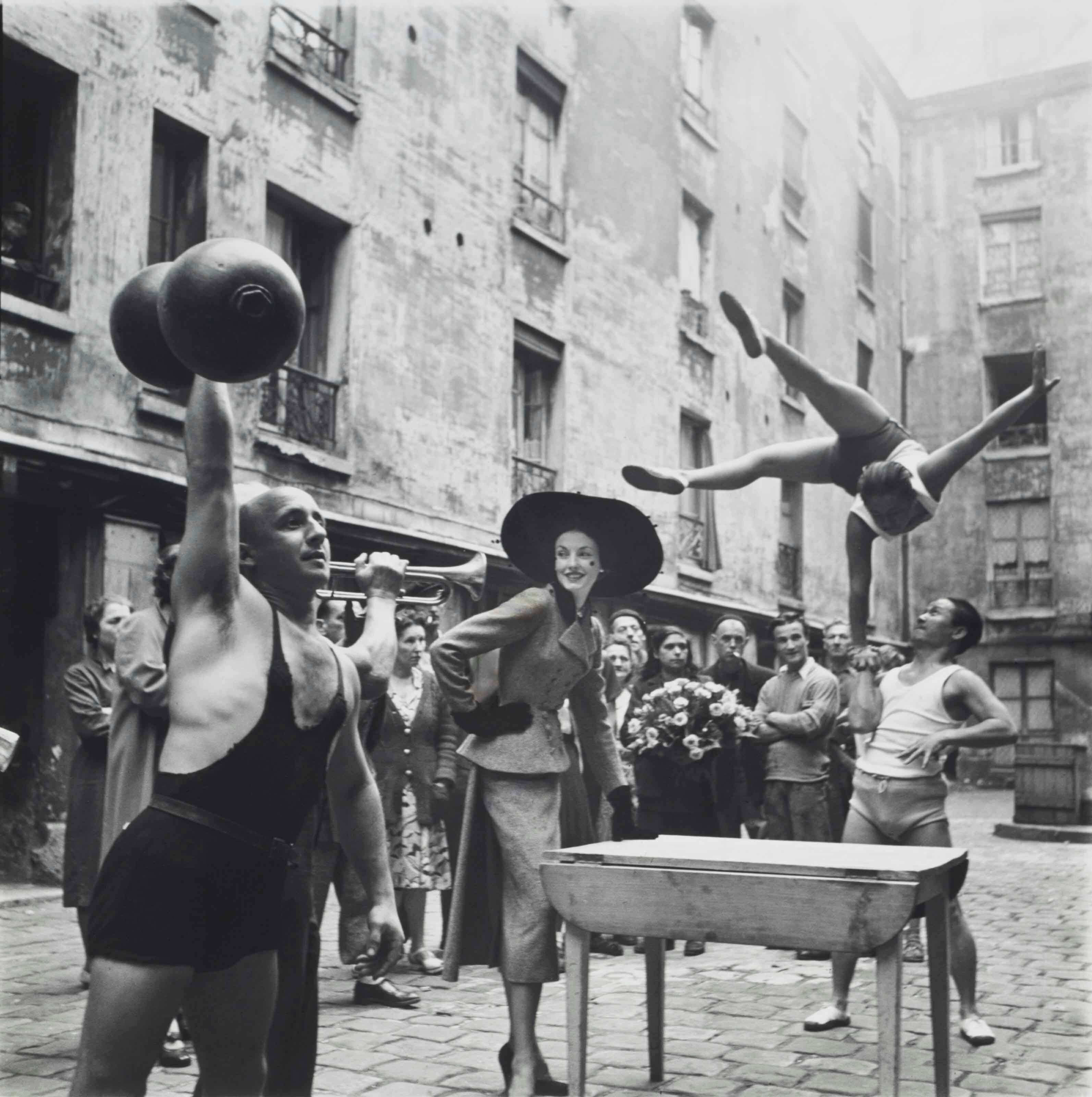 Элиз Дэниелс с уличными артистами, Костюм от Balenciaga, Марэ, Париж, август 1948 года.  Фотограф Ричард Аведон