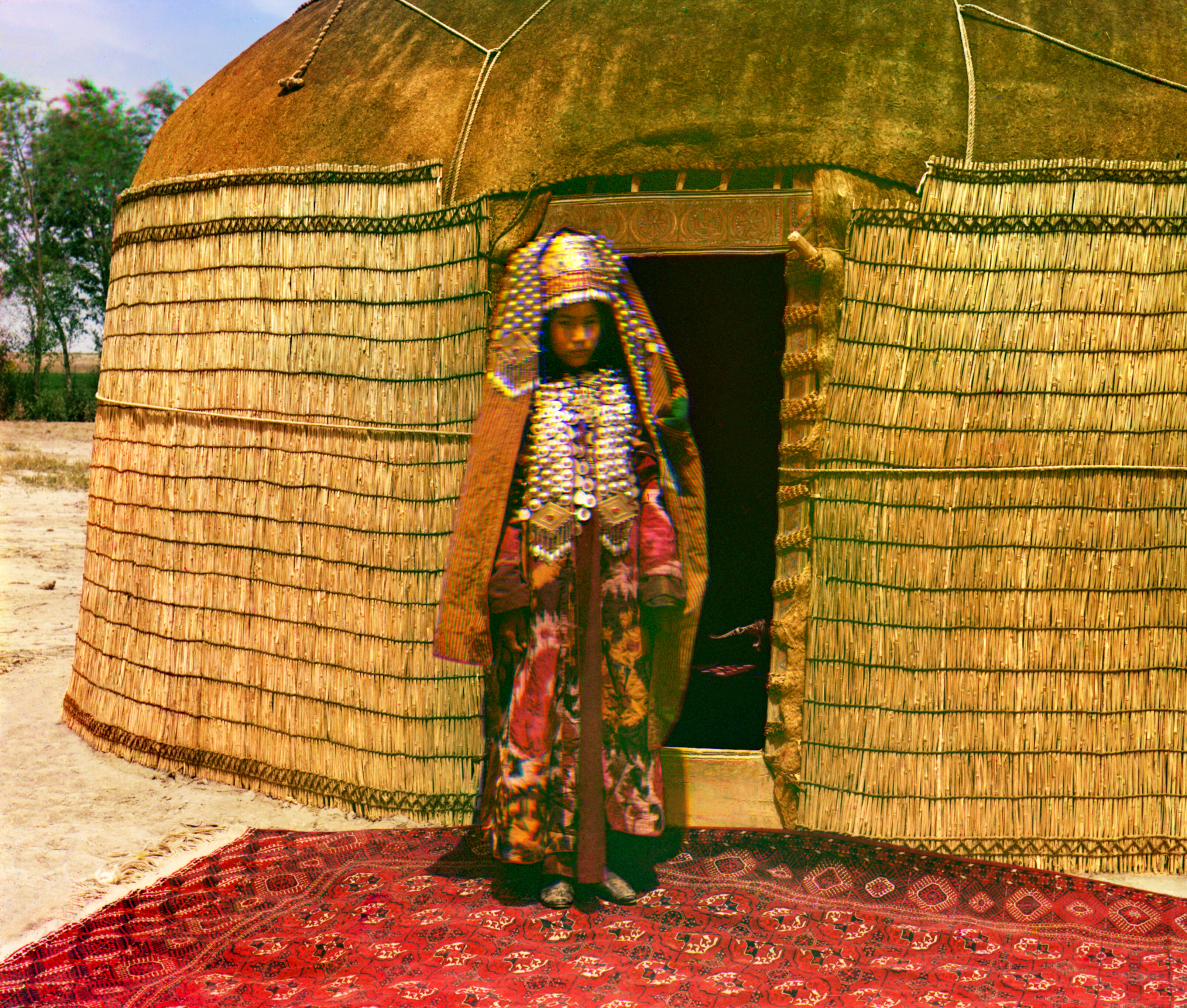 Женщина в традиционной одежде и украшениях стоит на ковре перед юртой, 1905-1915, фотограф Сергей Прокудин-Горский