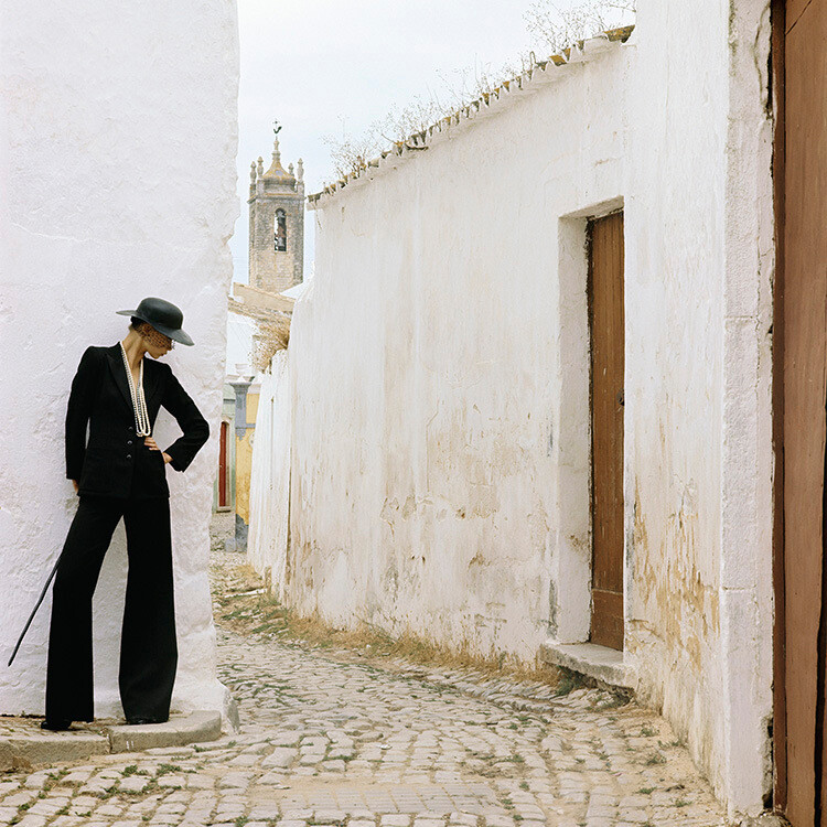 В черном костюме, шляпе и жемчуге в переулке в Португалии для Vogue, январь 1973 года. Фотограф Норман Паркинсон