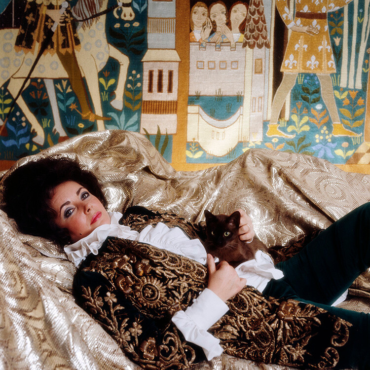 Элизабет Тейлор в платье Soldano в своем номере в отеле Duna InterContinental в Будапеште с гобеленом, созданным венгерским художником Иштваном Баном. 25 февраля 1972 года. Фотограф Норман Паркинсон