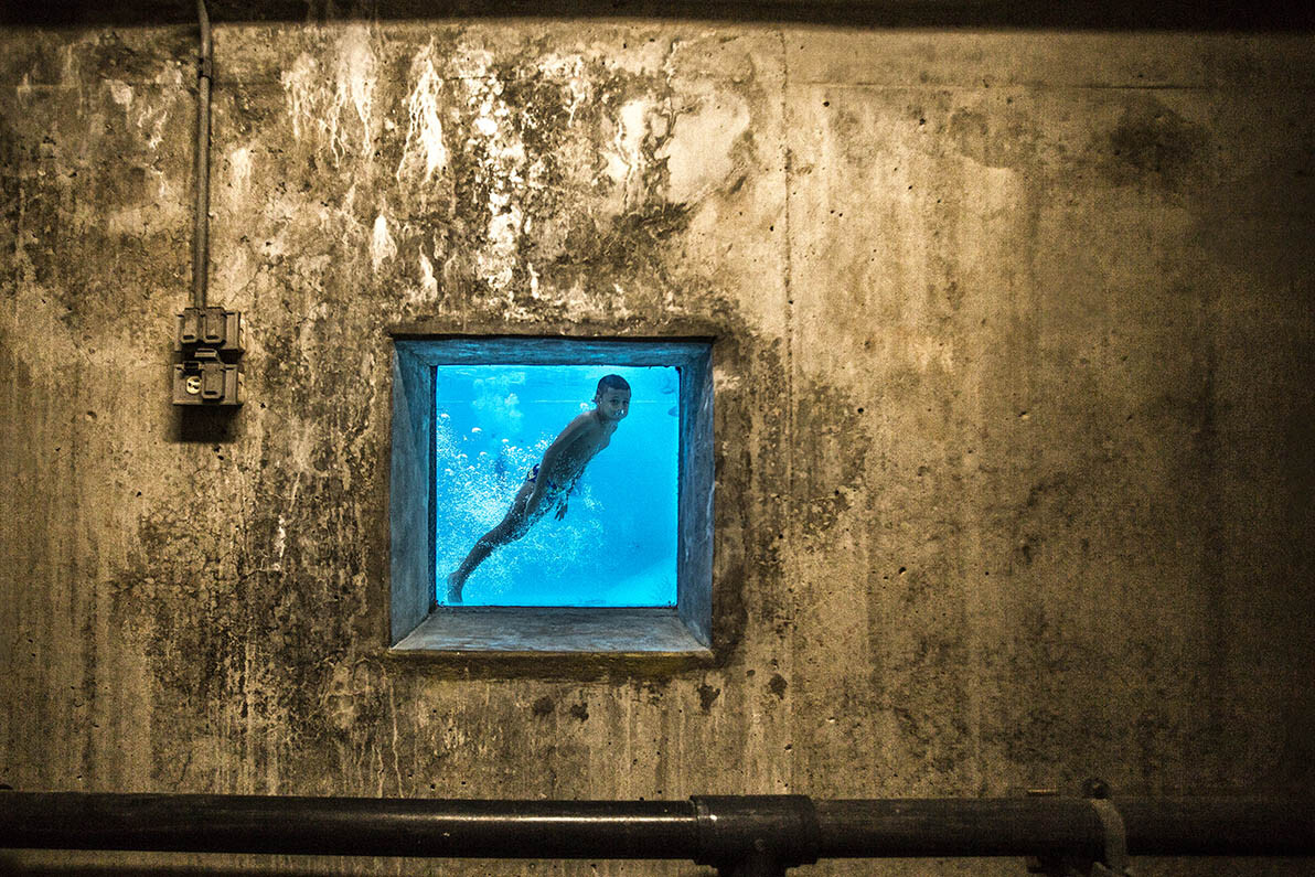 2 место в категории «Уличная фотография», 2021. «По другую сторону». Мальчик в общественном бассейне в Медельине, Колумбия. Автор Педро Лондоньо
