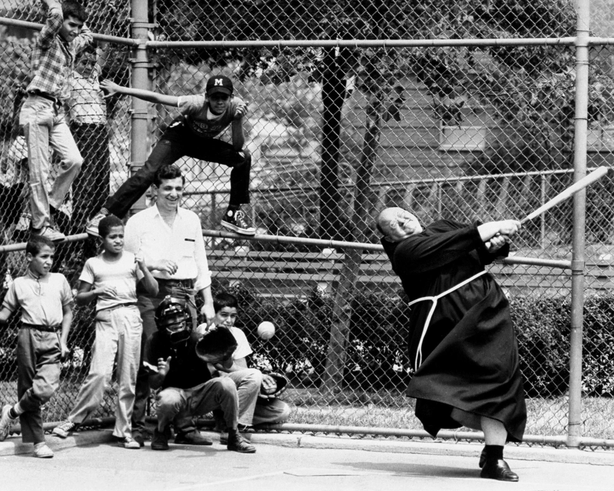 Преподобный Капистран Феррито играет в бейсбол на детской площадке в Нью-Йорке, 1960-е. Фотограф Джон Дюпри