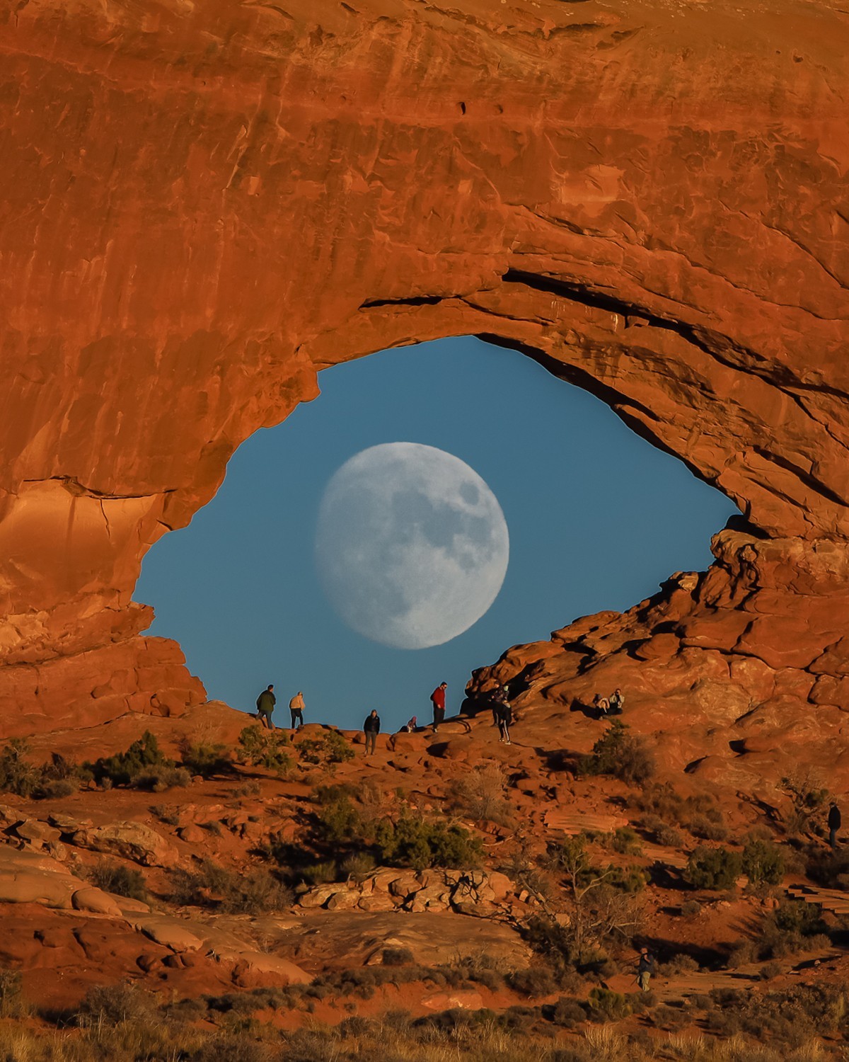 Луна, похожая на гигантский глаз, смотрящий через скальную арку в пустыне. Национальный парк Арчес, Юта. Фотограф Зак Кули