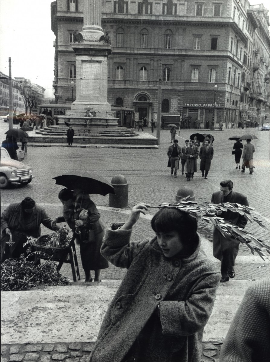 Девушка купила зеленую веточку, и, поскольку начинается дождь, она покрывает ею голову, Рим, Италия, 1958. Фотограф Леонард Фрид