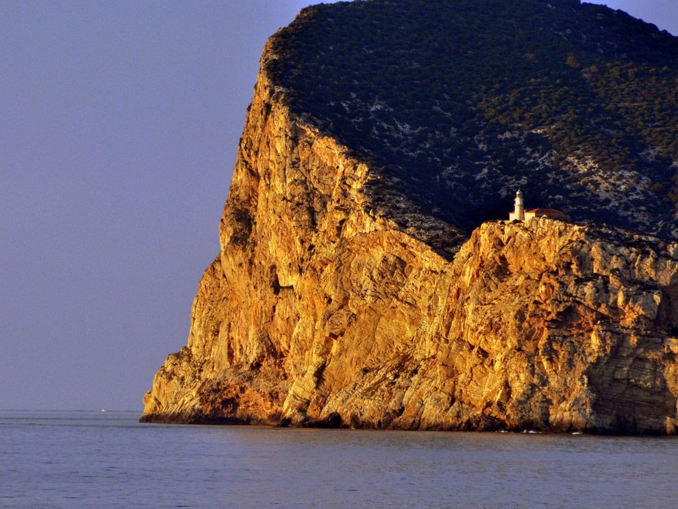 Солнце освещает морскую скалу и маяк в Испании. Фотограф Люси Уайт
