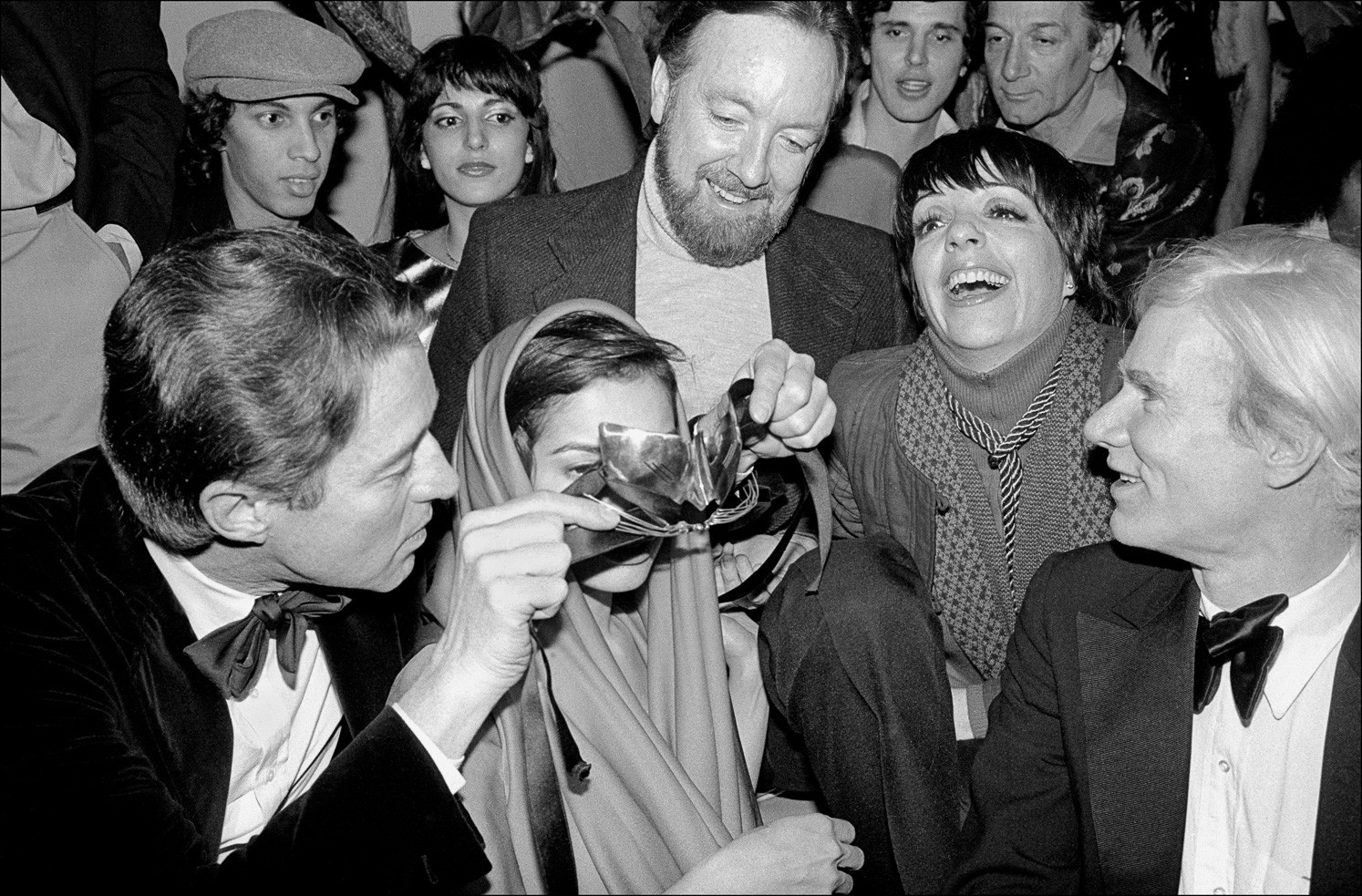Джек Хейли-младший, Лайза Миннелли и Энди Уорхол смеются, когда Холстон надевает маску на глаза Бьянки Джаггер на новогодней вечеринке Студия 54. Фотограф Аллан Танненбаум