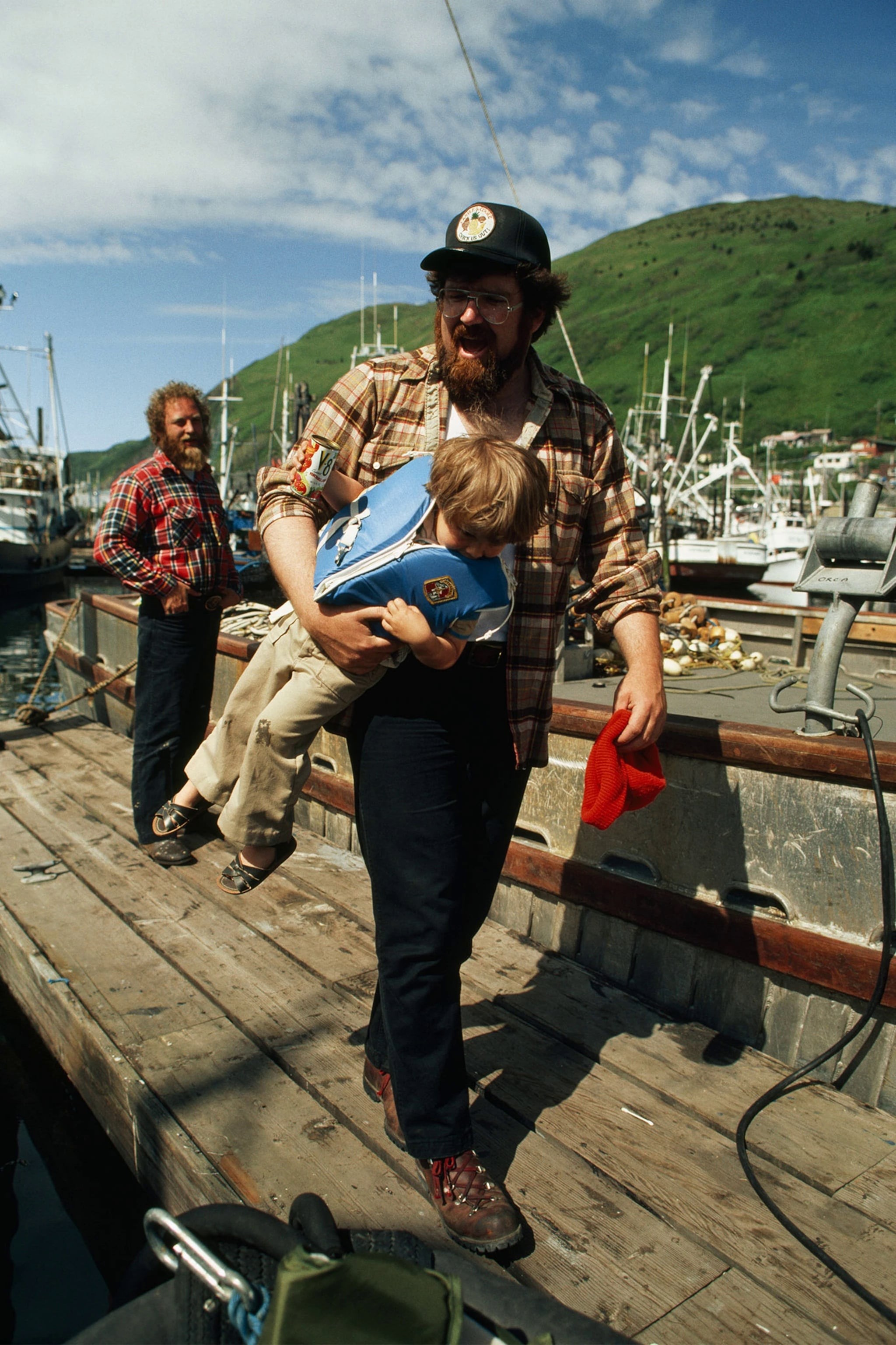 Отец несёт своего сына на пирсе. Остров Кадьяк, Аляска, 1970-е. Фотограф Стив Реймер