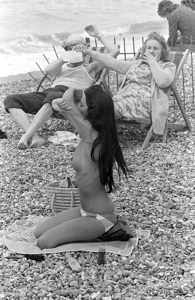Женщина закрывает глаза мужчины вязанием при виде раздевающейся девушки, 1974