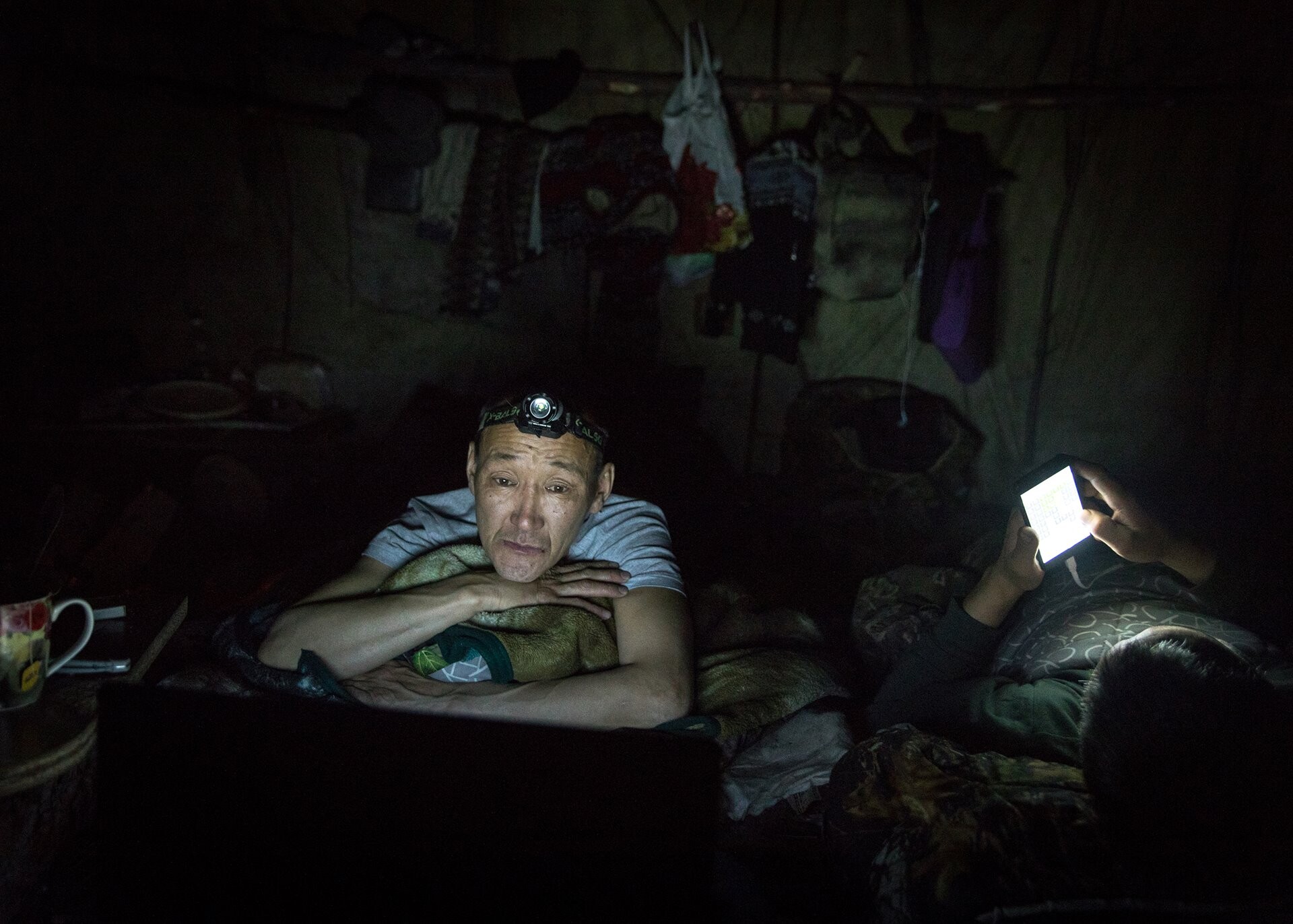 Охотник Григорий Замятин смотрит фильм на своём ноутбуке в палатке перед сном, Саха. Фотограф Алексей Васильев
