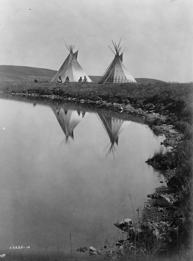 Два вигвама и индейцы пиеганы у пруда. Монтана, 1910. Фотограф Эдвард Кёртис