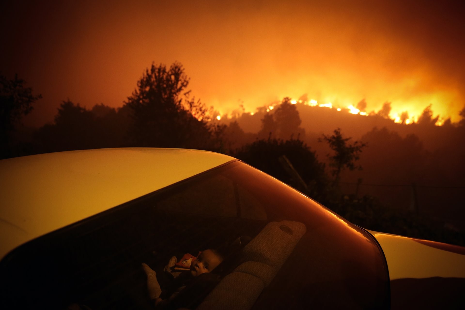 3 место в категории Главные новости, 2021. Ребёнок в машине на фоне лесного пожара в Оливейра-де-Фрадеш, Португалия. Автор Нуно Андре Феррейра
