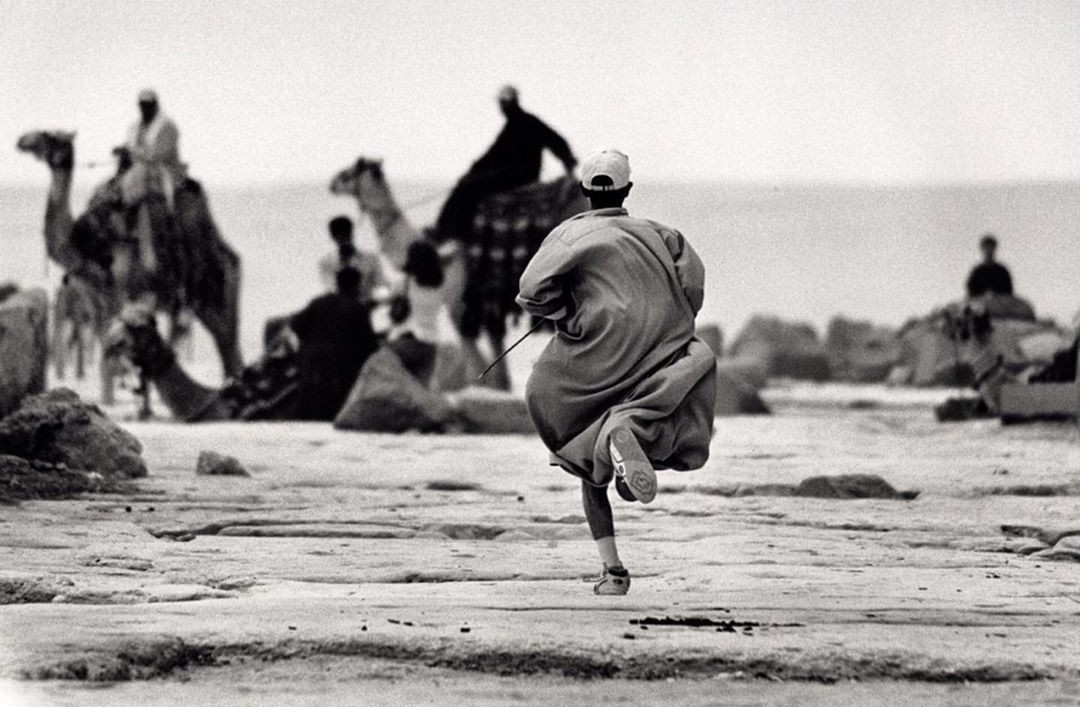 Молодой человек бежит за своим отцом на верблюде. Пирамиды Гизы, Египет. Автор Уолтер Ротуэлл