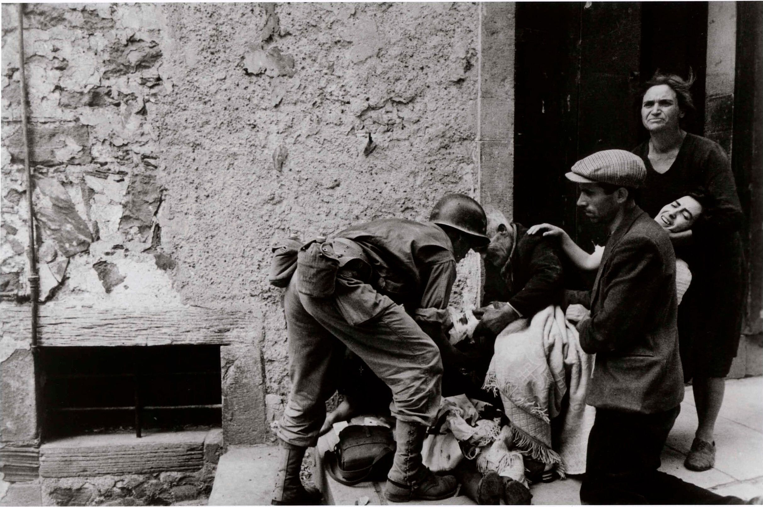 Солдат помогает группе людей, сидящих на ступеньках, Никосия, Сицилия, июль 1943 года. Фотограф Роберт Капа