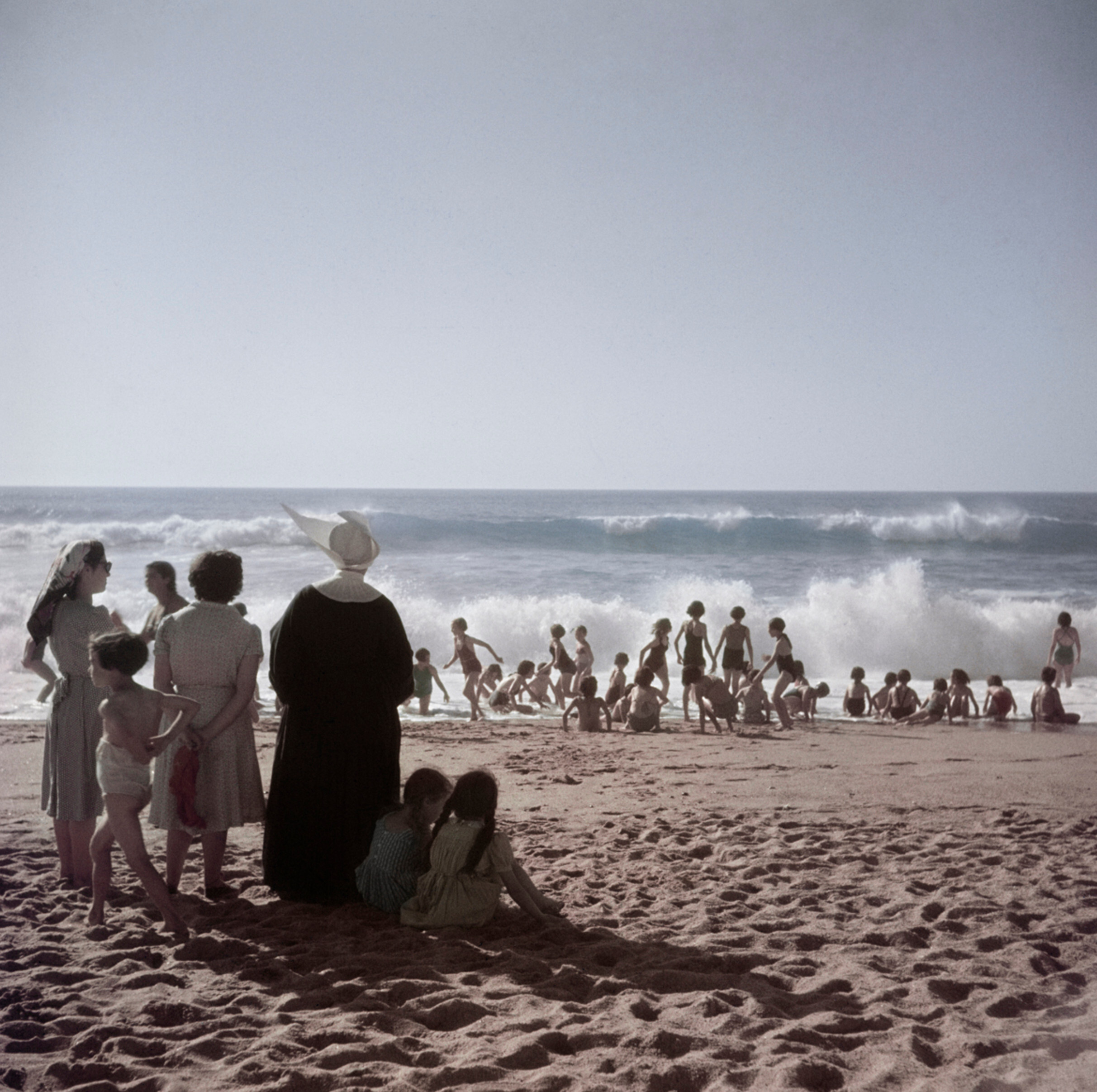 Монахиня и купальщицы на пляже, Биарриц, Франция, август 1951 года.  Фотограф Роберт Капа