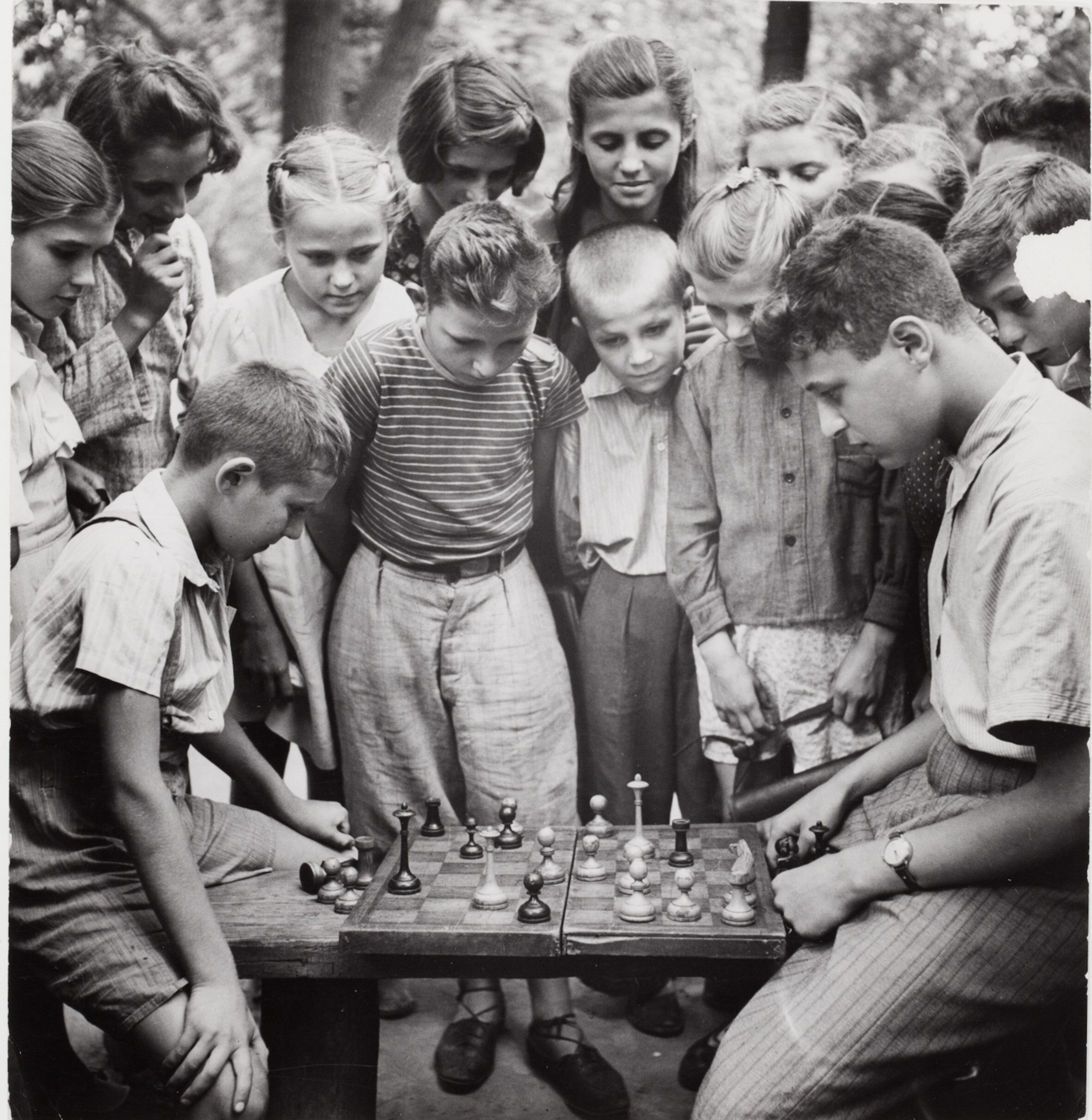 Два мальчика играют в шахматы на скамейке в парке перед толпой зрителей, Москва, 1947 год. Фотограф Роберт Капа