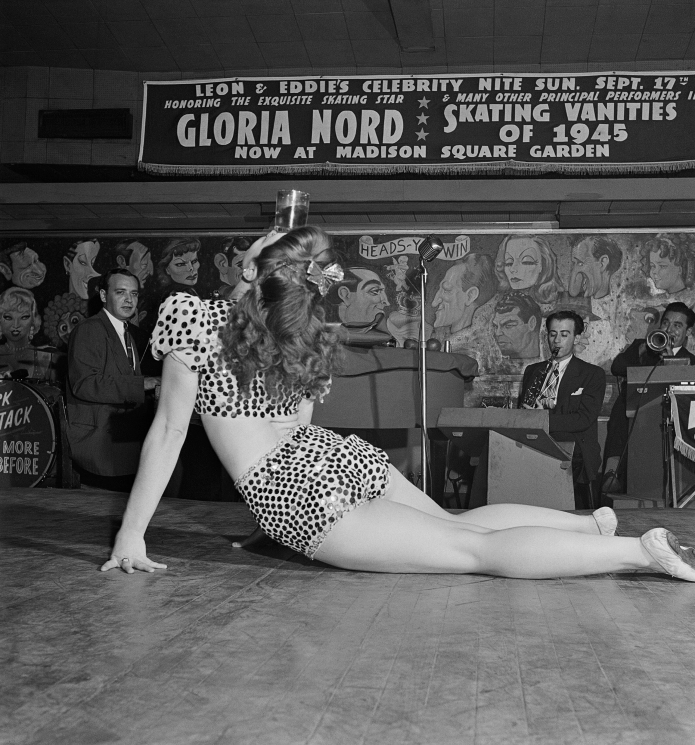 Танцовщица бурлеска развлекает военнослужащих и других посетителей, балансируя стаканом на голове, ночной клуб Леона Эдди, 52-я улица, Нью-Йорк, 1945 год. Фотограф Роман Вишняк