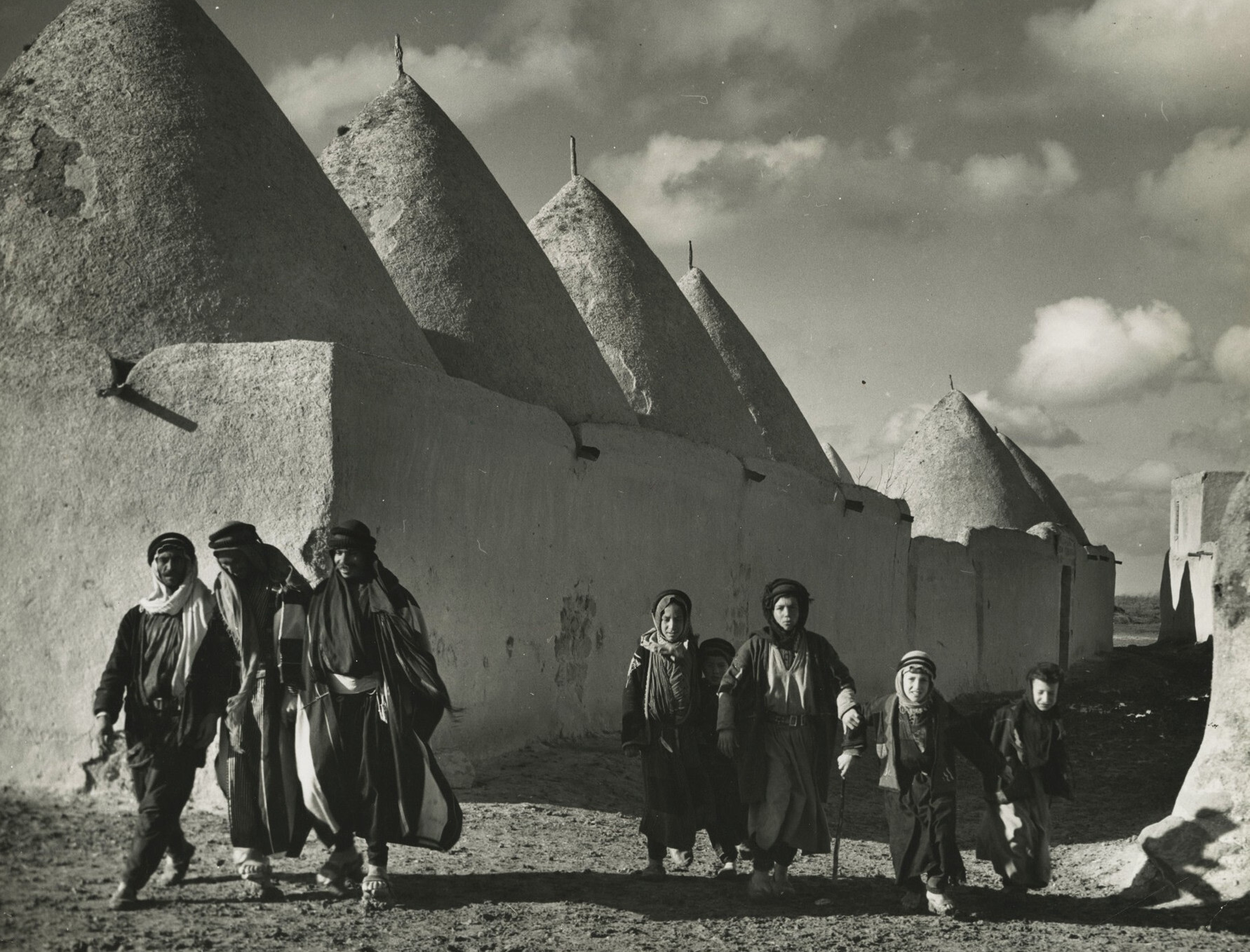 Сирийская семья, идущая по дороге мимо обнесенных стенами домов в форме старого финикийского города, 1940 год. Фотограф Маргарет Бурк-Уайт