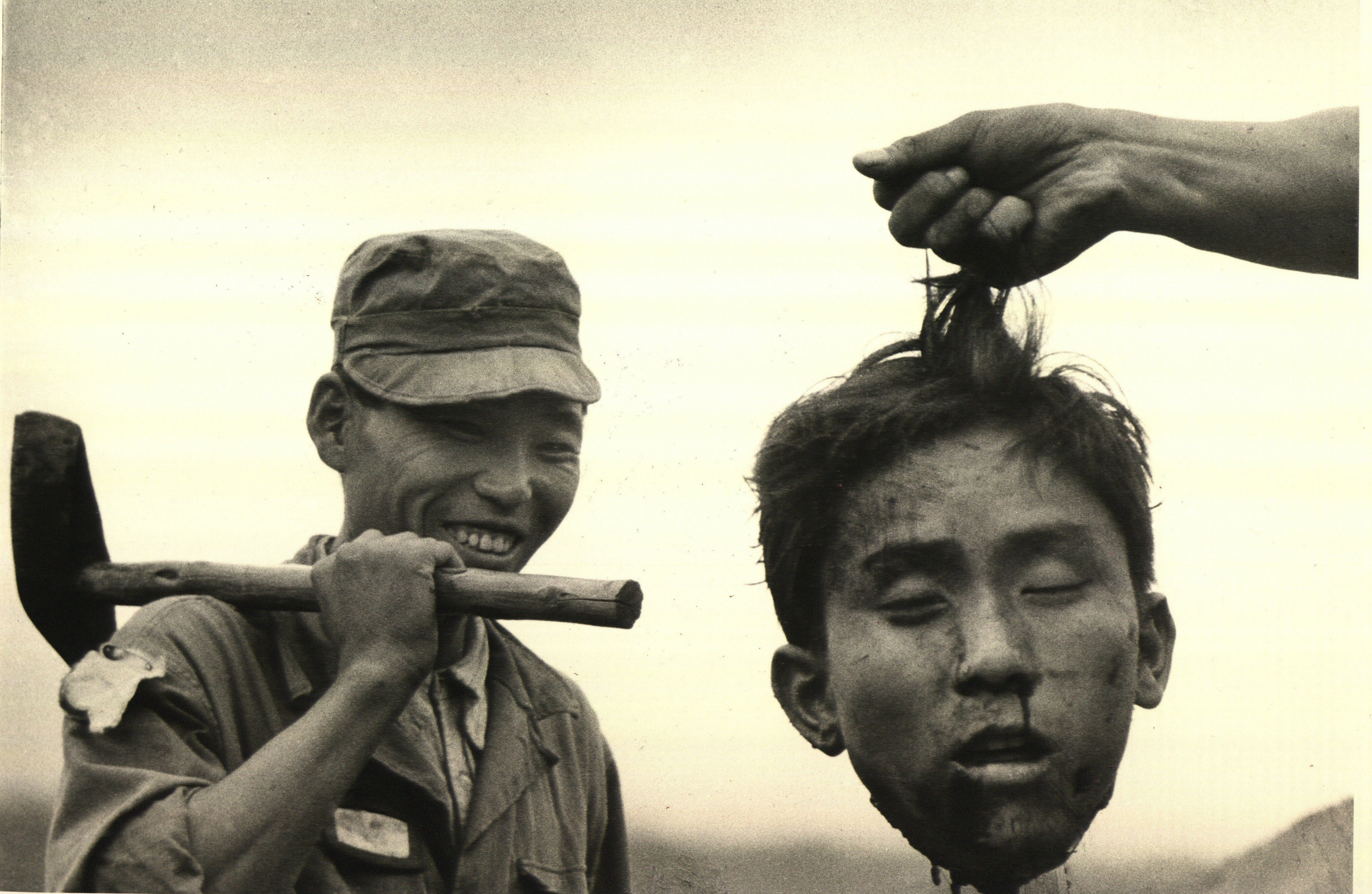 Южнокорейская национальная полиция держит отрезанную голову северокорейского коммуниста, которого они убили, 1951 год. Фотограф Маргарет Бурк-Уайт