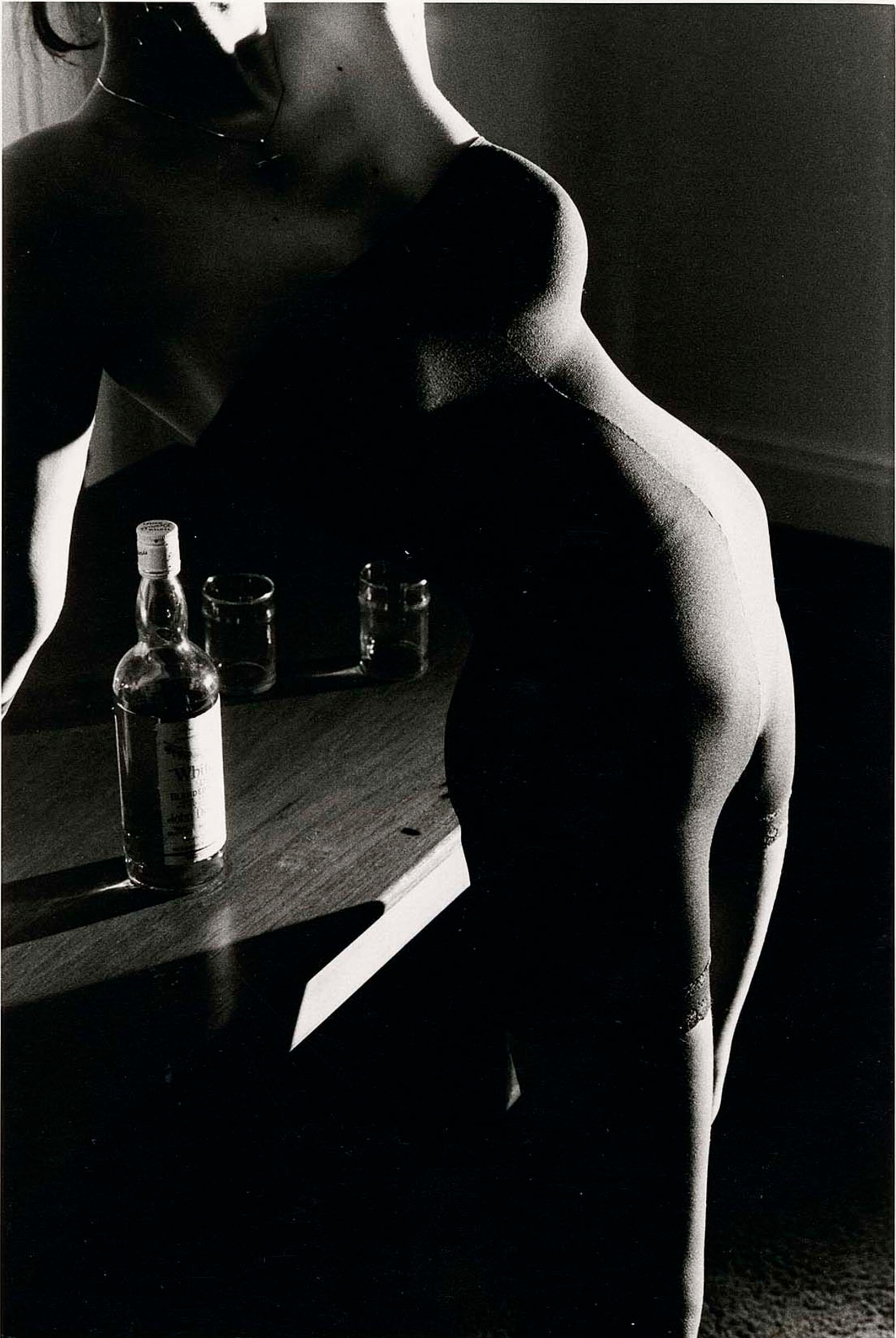 Женщина в нижнем белье опирается на стол с бутылкой алкоголя, 1986 г. Фотограф Дэвид Сайднер