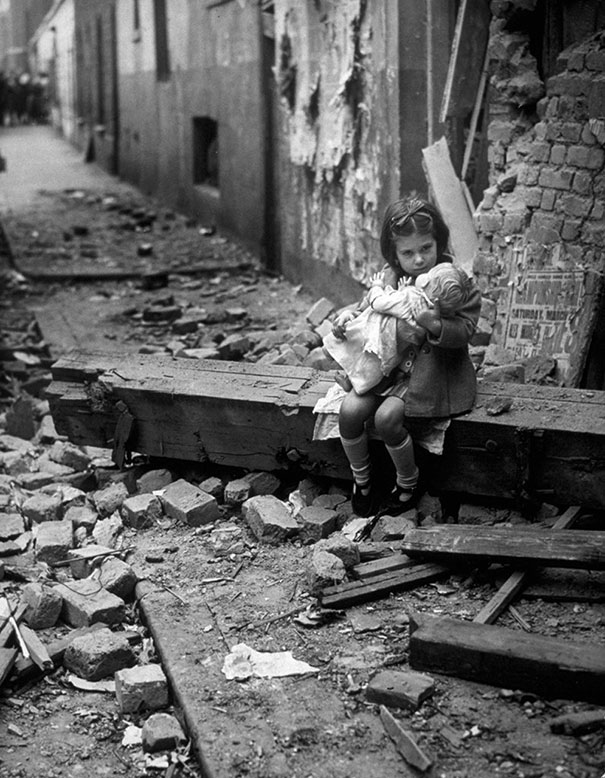 Маленькая девочка с куклой сидит в руинах своего дома после бомбёжки, Лондон, 1940