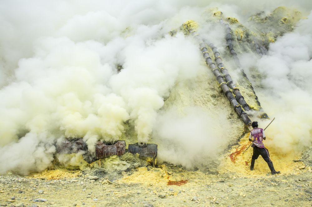 Rabochii sobiraet seru v kratere vulkana Idzhen v Indonezii